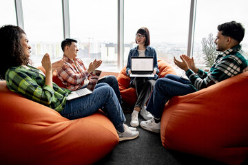 Diverse group of professionals clapping hands while female expert feeling grateful with digital...