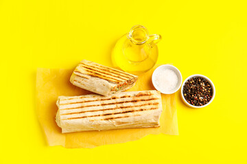 Baking paper with tasty shawarma on yellow background
