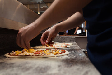 Obraz na płótnie Canvas Food concept. Preparing traditional italian pizza. Chef in uniform in interior of modern restaurant kitchen. Ready to eat