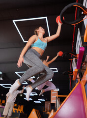 Young sports woman throws ball into ring in trampoline center