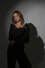 Fashion portrait of beautiful female model wearing black bomber jacket and trousers under spotlight. Female beauty, fashion and glamour concept.	