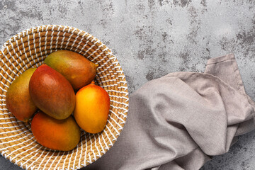 Bowl of fresh ripe mangoes on grunge background