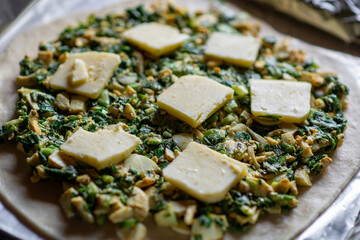 Pie with green onion and egg. Cooking a pie. Pieces of butter are on top.