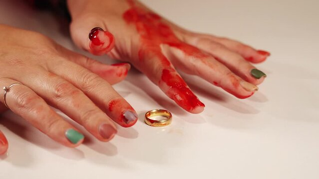 Trembling young woman hands with bloody fingers over ring