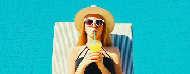 Summer vacation, happy relaxing young woman lying on deckchair drinking fresh juice on pool background