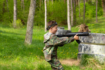 Boy weared in camouflage playing laser tag in special forest playground.