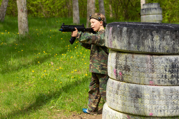 Boy weared in camouflage playing laser tag in special forest playground.