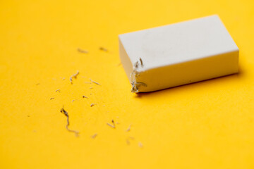 White eraser on a yellow background. Rubbish from erasure. - Powered by Adobe