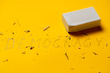 Democracy and an eraser on a yellow background. The disappearance of democracy concept.
