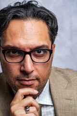 portrait of a serious dark-haired man in glasses.