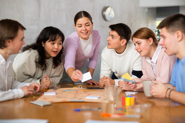 Group of positive younger people playing tabletop game