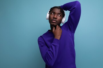 well-groomed dark-skinned European young brunette man with dreadlocks with wireless headphones