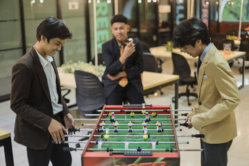 Coworker playing foosball table soccer game during a work break at the office. 