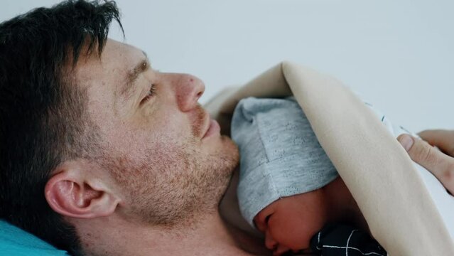 Happy Caucasian father is holding his little baby on his chest. Skin to skin practice for newborn after mom had C-section operation. Close up.