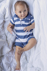 Smiling baby boy lying on a bed sleeping on white sheets. The concept of children and birth. 