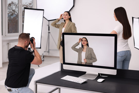 Professional photographer and assistant working with beautiful model in modern photo studio, selective focus
