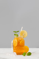 A glass of cold tea, ice cubes, lemon slices and a sprig of mint. Cooling summer drinks.