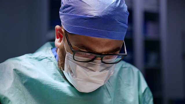 Upper part of a male surgeon wearing eyeglasses. Doctor&rsquo;s portrait focused on operation. Close up.
