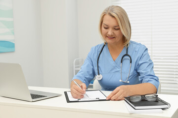 Doctor writing at white table in clinic