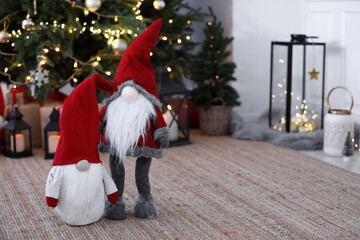 Obraz premium Cute Scandinavian gnomes on carpet near Christmas tree indoors