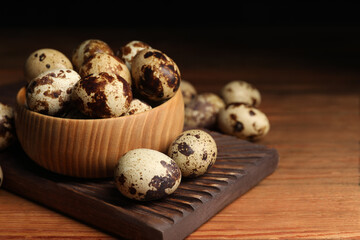 Obraz premium Bowl and many speckled quail eggs on wooden table. Space for text