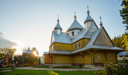 Fototapeta na wymiar The wooden church is painted yellow with a silver dome. Warm sunny evening
