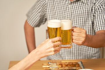 自宅でビールで乾杯をする熟年夫婦の手元のクローズアップ