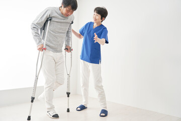 松葉杖を使って歩くリハビリをする中年男性