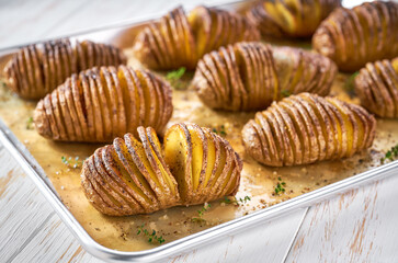 baked Hasselback potato on a baking tray, close up. Classic roasted Hasselback potato.