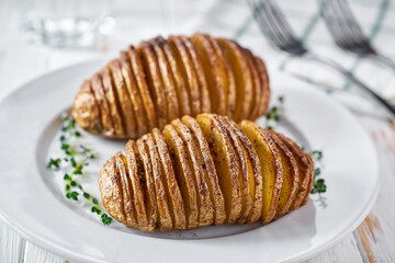 baked Hasselback potato in a plate, close up.