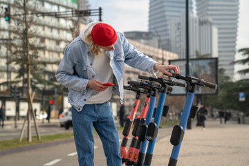 Millennial guy taking electric scooter while traveling alone in Europe, standing at e-scooter...