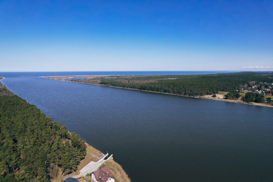 Aerial view drone of river goes into the sea. Delta of Vistula river goes in Baltic Sea in Sobieszewo Gdansk Poland. Forest and small village around river