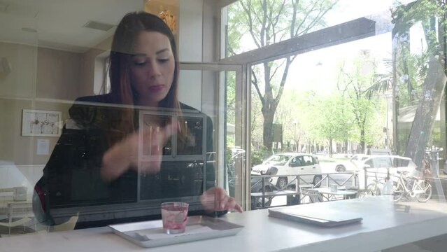 young woman eating a sweet in a bar near the window footage