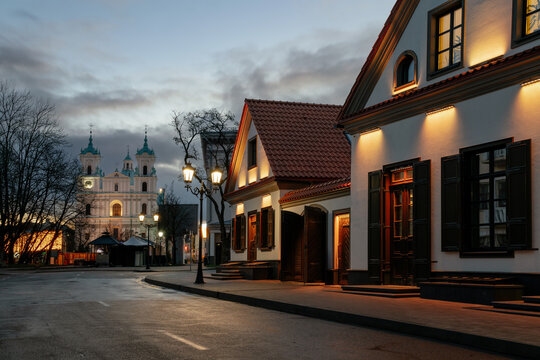 View of the recreated historical buildings on Zamkovaya Street and the Cathedral of St. Francis Xavier in the background at dusk with night lighting, Grodno, Belarus