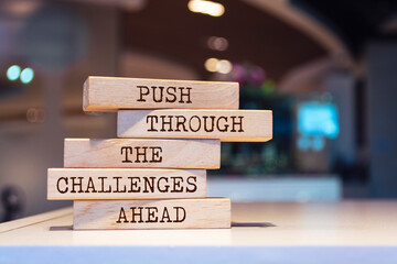 Wooden blocks with words 'Push through the challenges ahead'. Inspirational motivational quote.