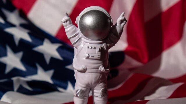 Zoom in out Plastic toy figure astronaut on American flag background Copy space. 50th Anniversary of USA Landing on The Moon Concept of out of earth travel, private spaceman commercial flights. Space