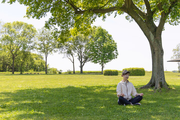 公園の木陰で瞑想ヨガをする女性