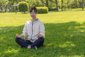 Obraz premium 公園の木陰で瞑想ヨガをする女性