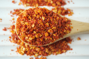 top view of chili flakes on wooden spoon on white 