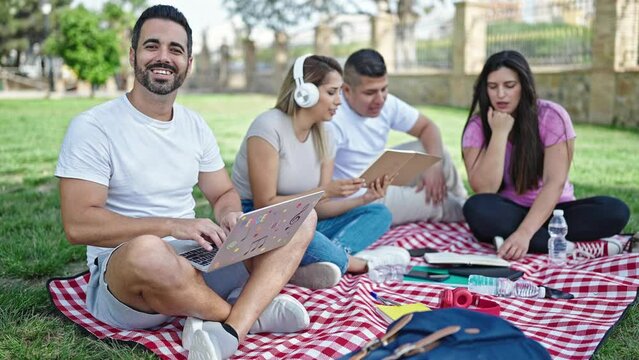 Group of people students using laptop reading book studying at park