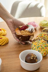 serving table with exquisite desserts among them cup with ice cream, cream and strawberry, congeeous cookies, and chocolate ball, appetizing sweet food in studio
