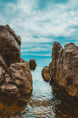 Fototapeta na wymiar Kvarner gulf of Adriatic sea rocky coastline, large rocks at shoreline in old town of Lovran in Croatia