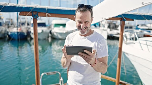 Middle age man smiling confident using touchpad at boat