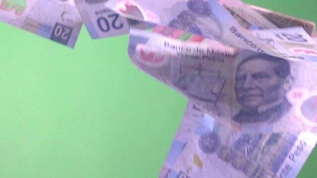 slow motion shot of Mexican bank notes falling against a green screen