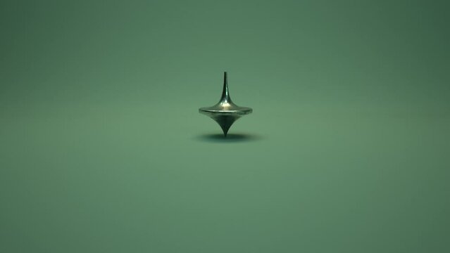 Spinning Top.  A weathered metal spinning top spins, slows, wobbles, falls and stops as camera pushes in.