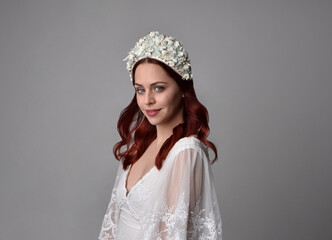 close up portrait of beautiful red haired model wearing elegant pearl wedding headdress on a studio background.