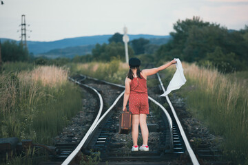 Fototapeta na wymiar A little girl in a dress walking on an abandoned railroad tracks.