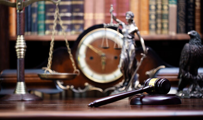 Obraz premium Lawyer office. Judge’s gavel, Themis sculpture and legal books in the bookshelf.