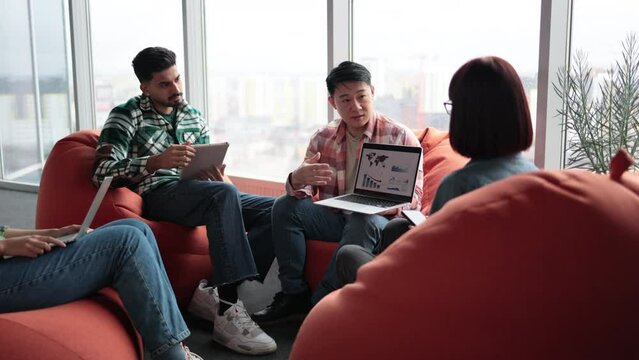 Close up of asian male explaining graphs and charts on digital screen while multiethnic workers enjoying presentation. Happy analytics professionals managing information in visual form in office.