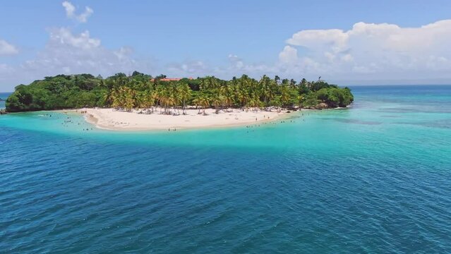 Aerial orbiting shot of exotic island named cayo levantado with palm trees and sandy beach surrounded by turquoise water at sunlight 